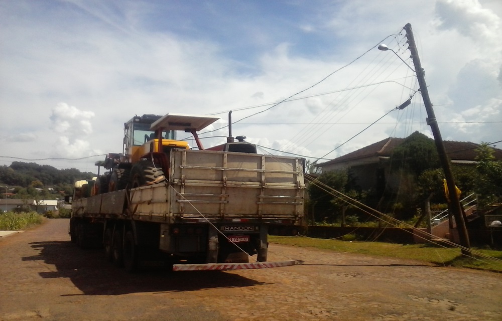Ir para  <p>Na tarde desta segunda-feira, por volta das 14h15min, uma carreta, de placas JOL-0921, que transportava uma carregadeira e um trator agr&iacute;cola, arrastou a fia&ccedil;&atilde;o e derrubou um poste de madeira na rua...